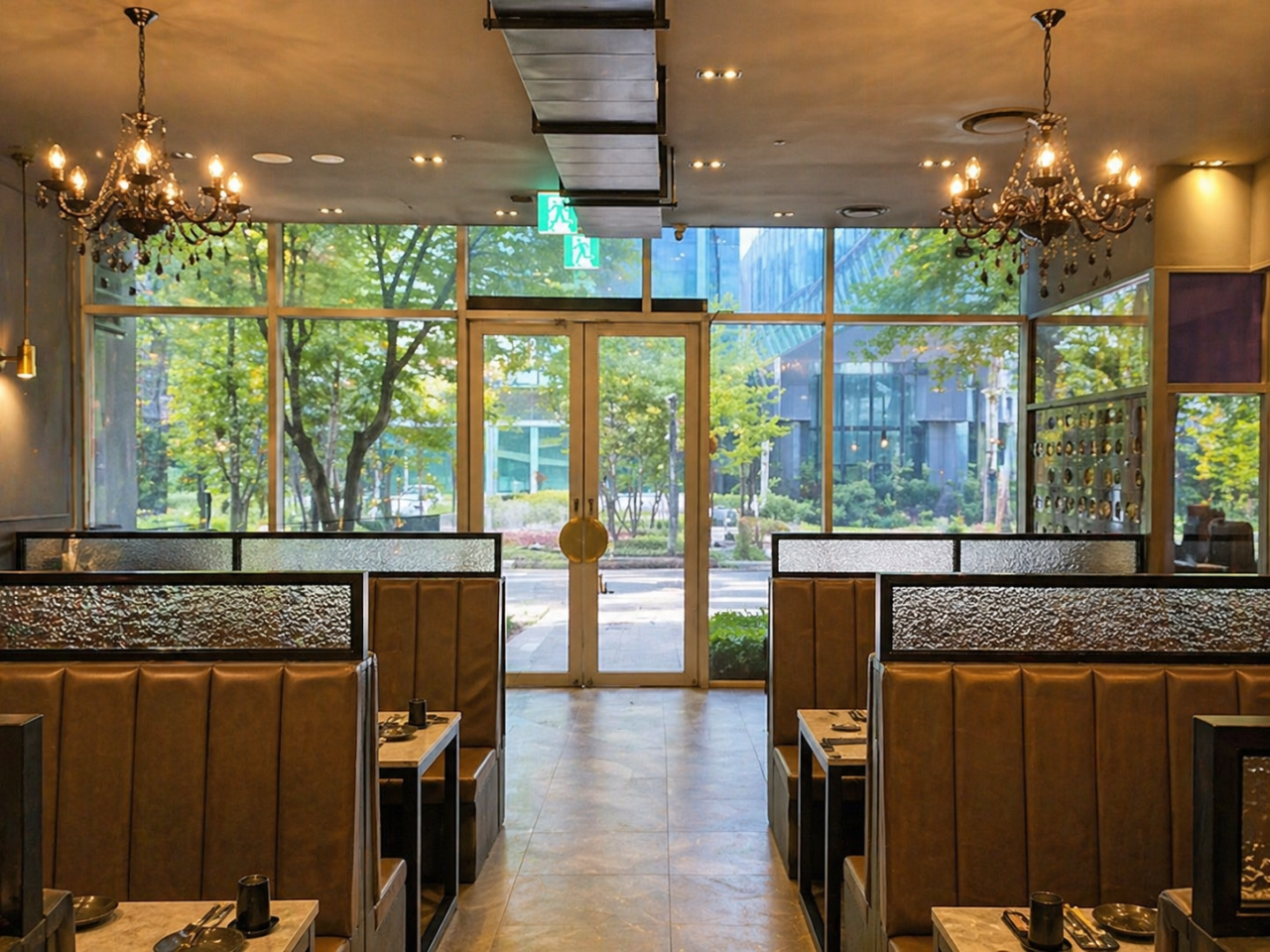 Main dining room with chandeliers and brown leather booths looking out to trees